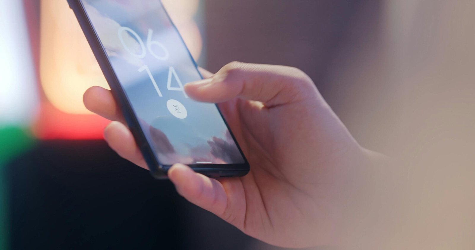 Close-up of a hand holding a smartphone locked with a fingerprint sensor.