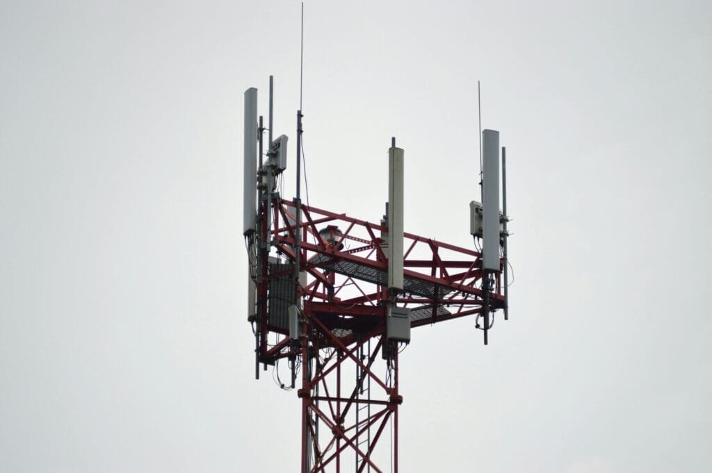 A red communication tower with antennas stands tall against a gray sky.