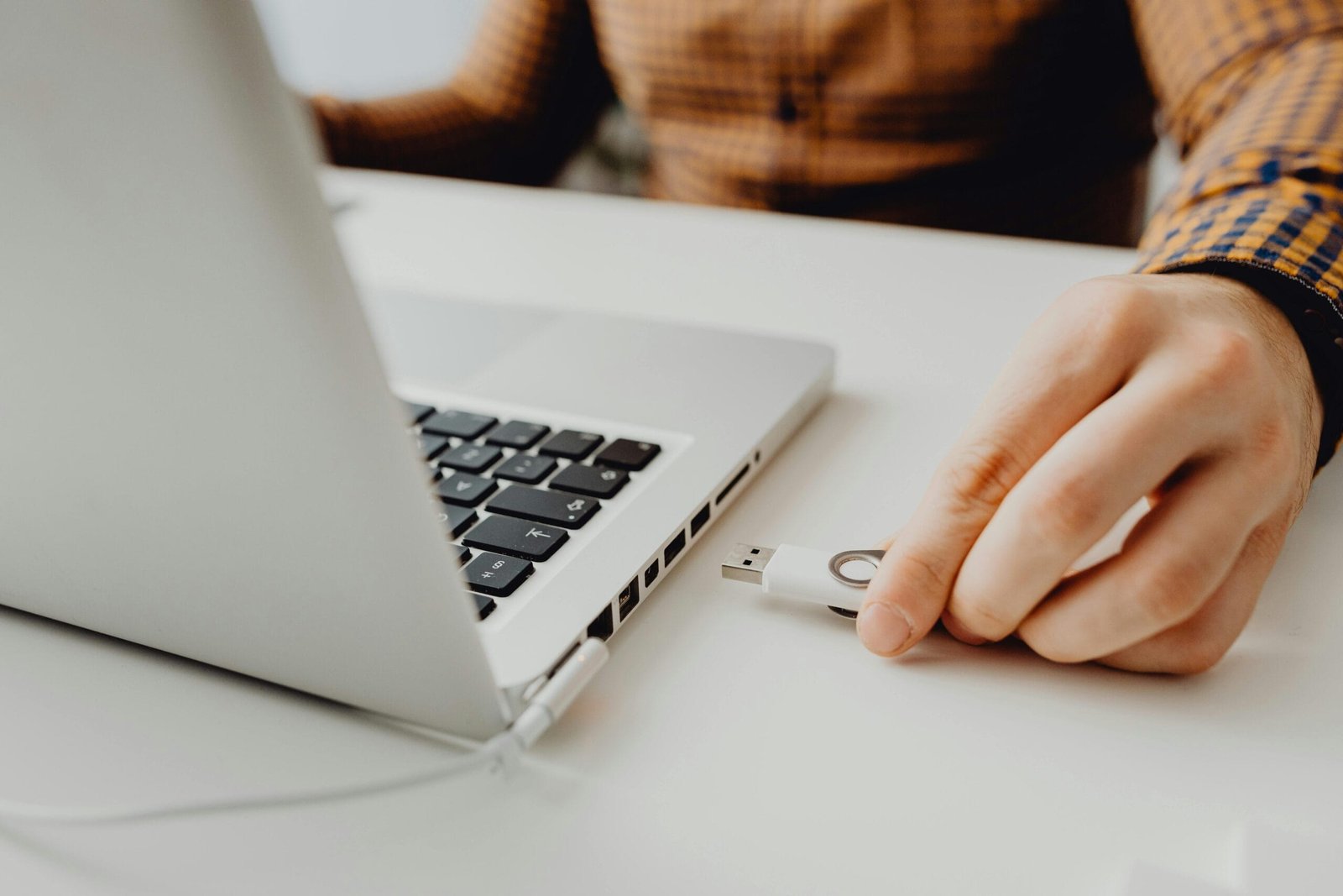 Close-up of a person inserting a USB drive into a laptop, symbolizing technology and data connection.