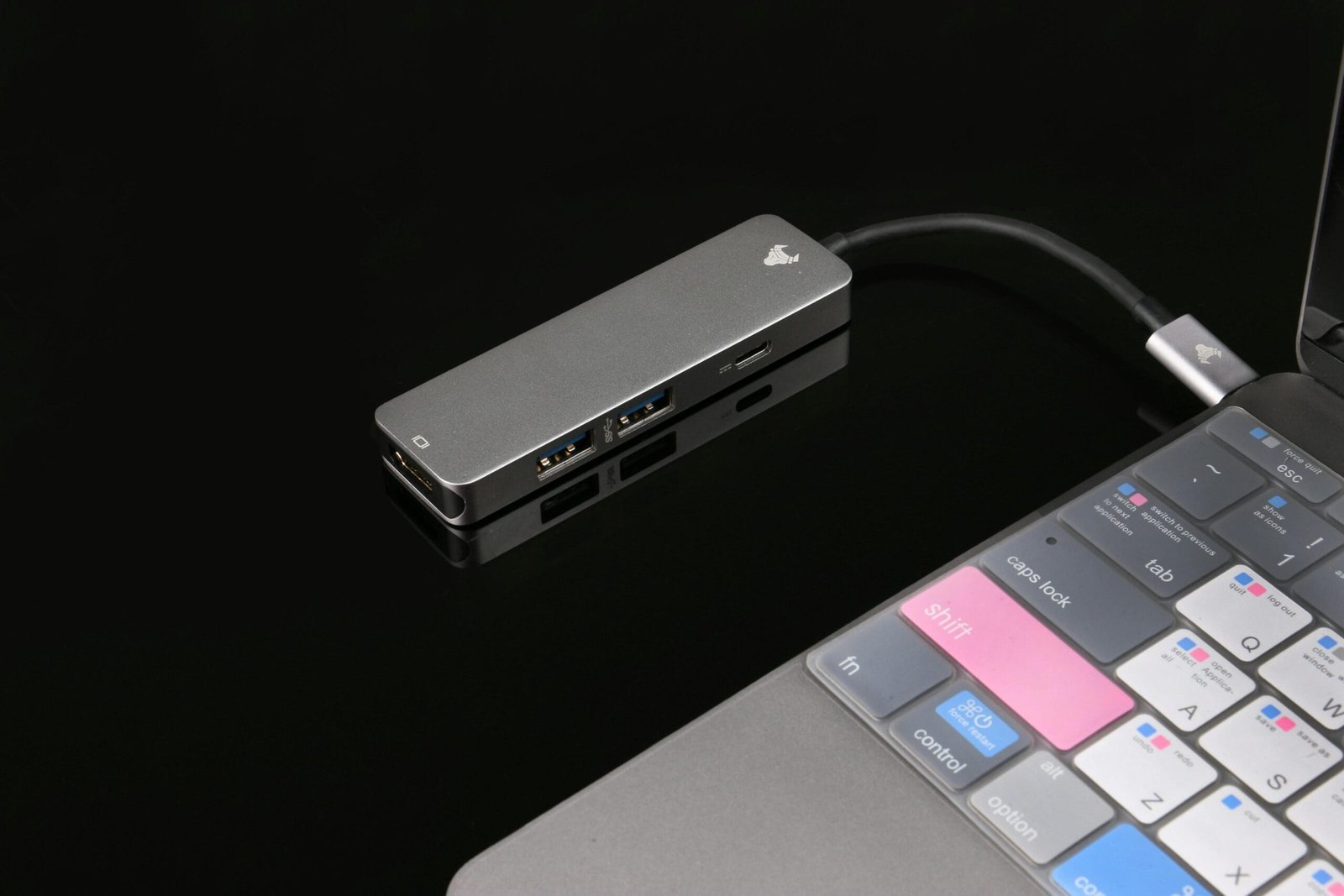 Sleek USB hub connected to a laptop, featuring tech elements on a glossy black surface.