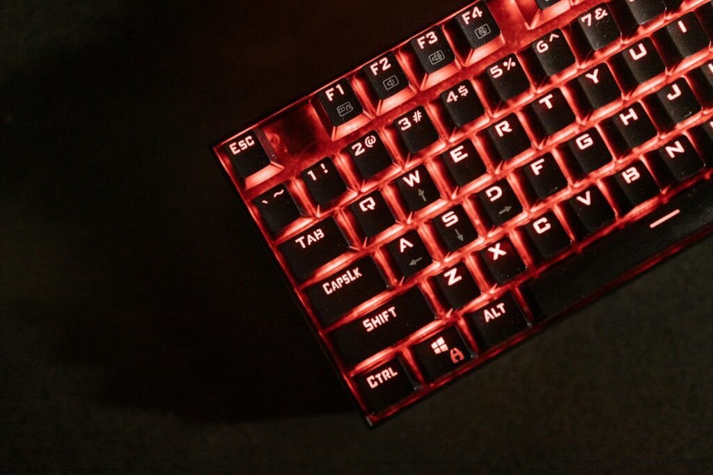 Close-up view of a red illuminated mechanical gaming keyboard in a dark room.